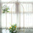 Gold floral arch with white and yellow flowers against a window backdrop.