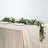Elegant table setting with greenery and roses on a neutral tablecloth.