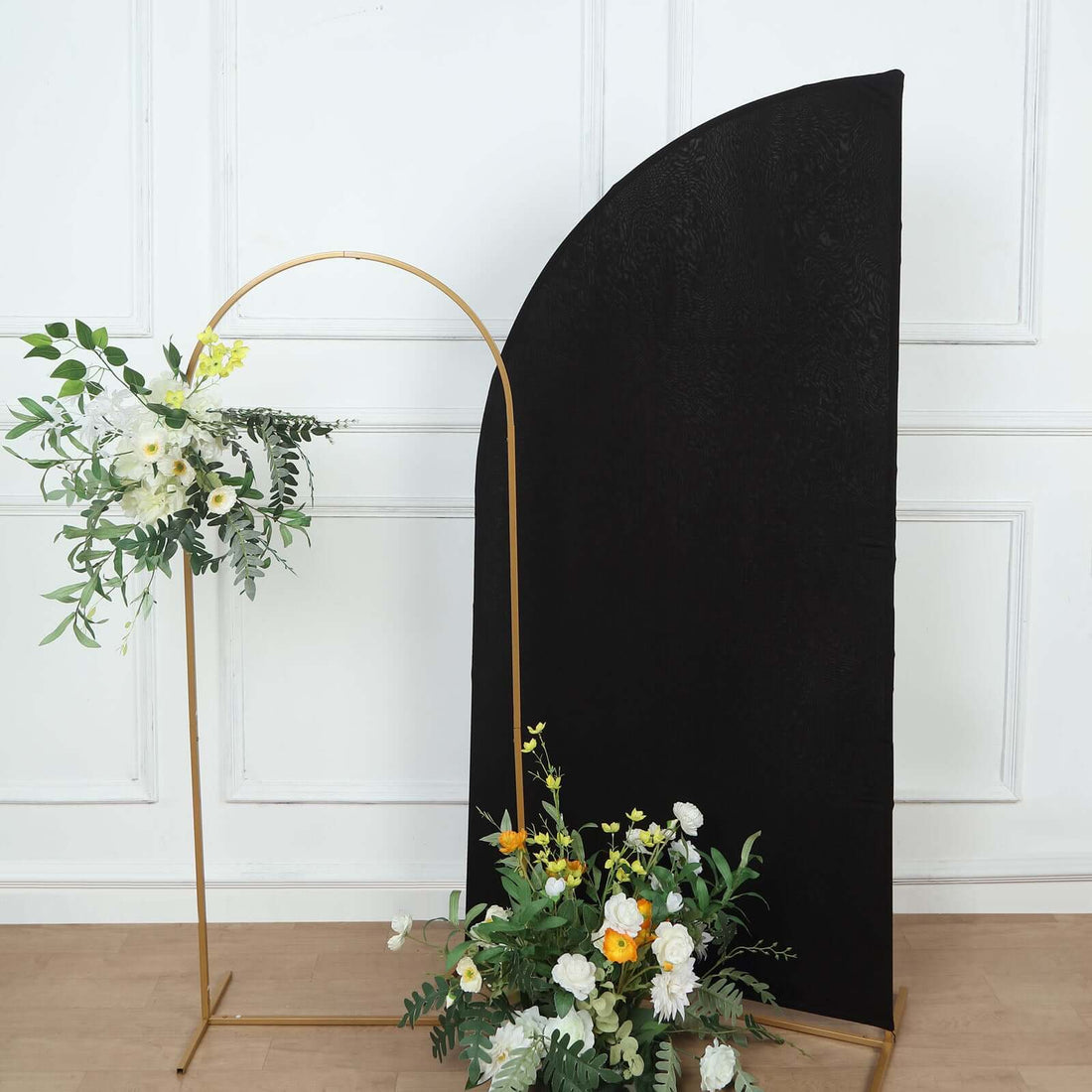Black curved backdrop with floral arrangement in a gold stand.