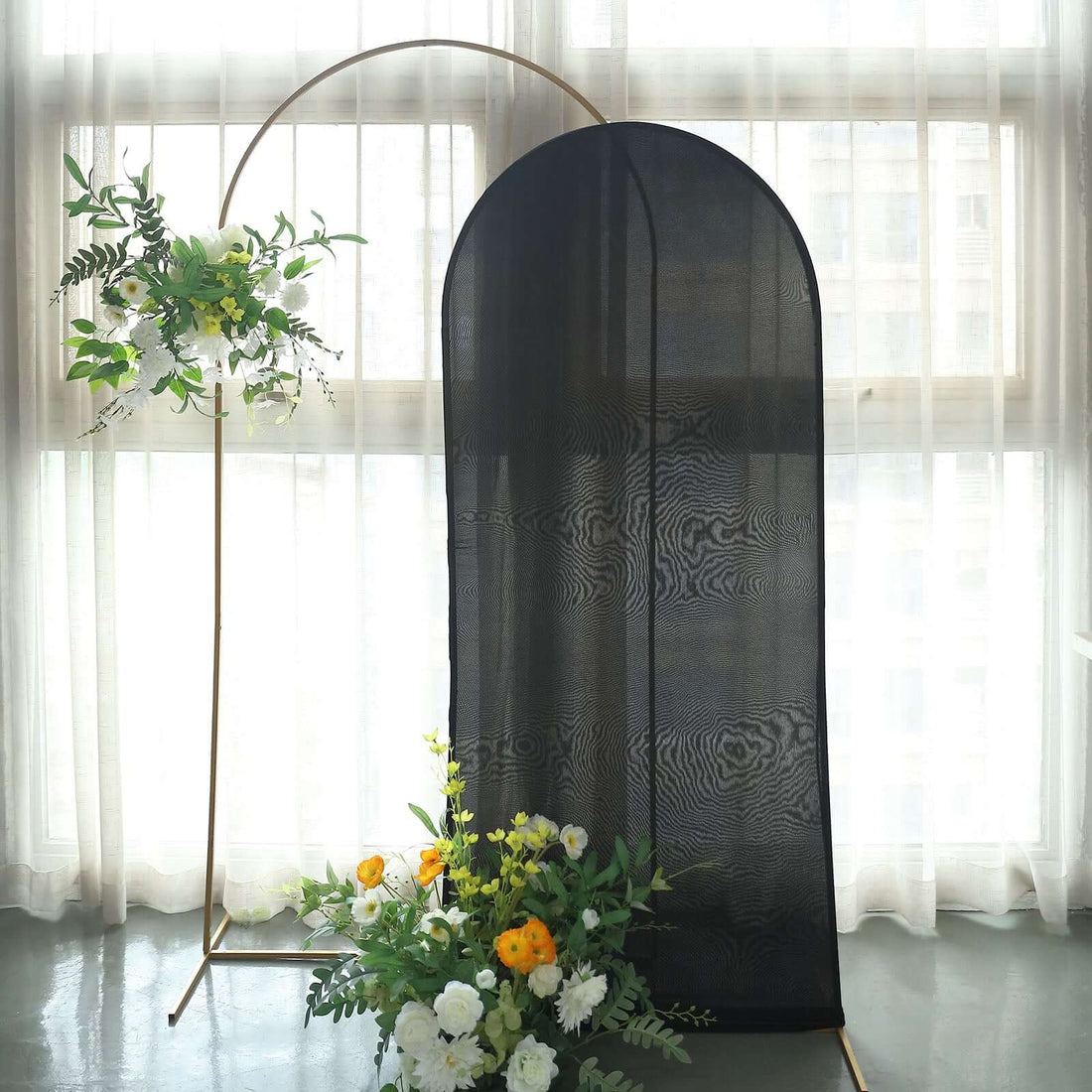 Black fabric backdrop with floral arrangement in a bright indoor setting.