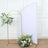 Floral arrangement with gold stand and backdrop in a studio setting.
