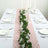 Table setting with pink lace runner and greenery, elegant dining arrangement.