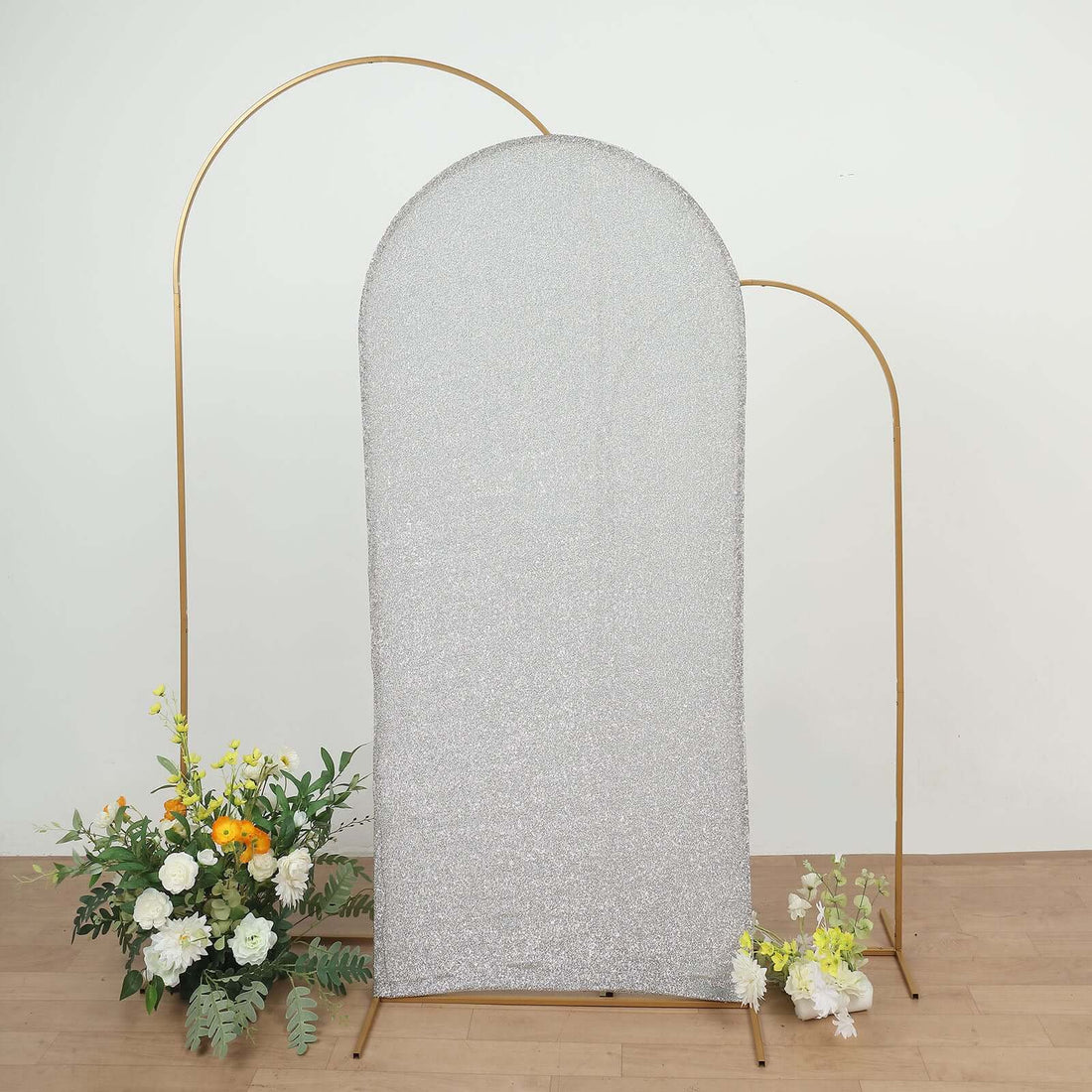 Silver glitter photo backdrop with gold arch and floral arrangement.