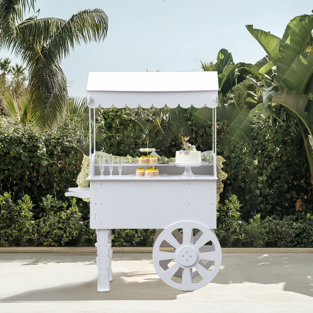 White dessert cart with a canopy and decorative treats in a lush garden setting.