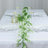 Elegant table setting with white plates and greenery centerpiece.