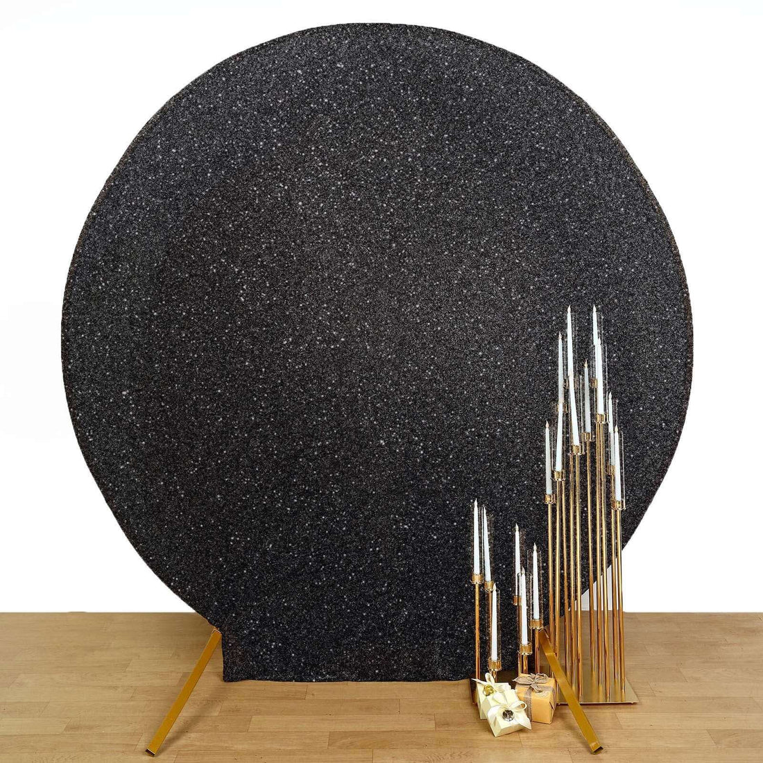 Black textured backdrop with gold candle holders and candles for photography.