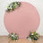 Round pink backdrop with floral arrangements at the top and bottom.