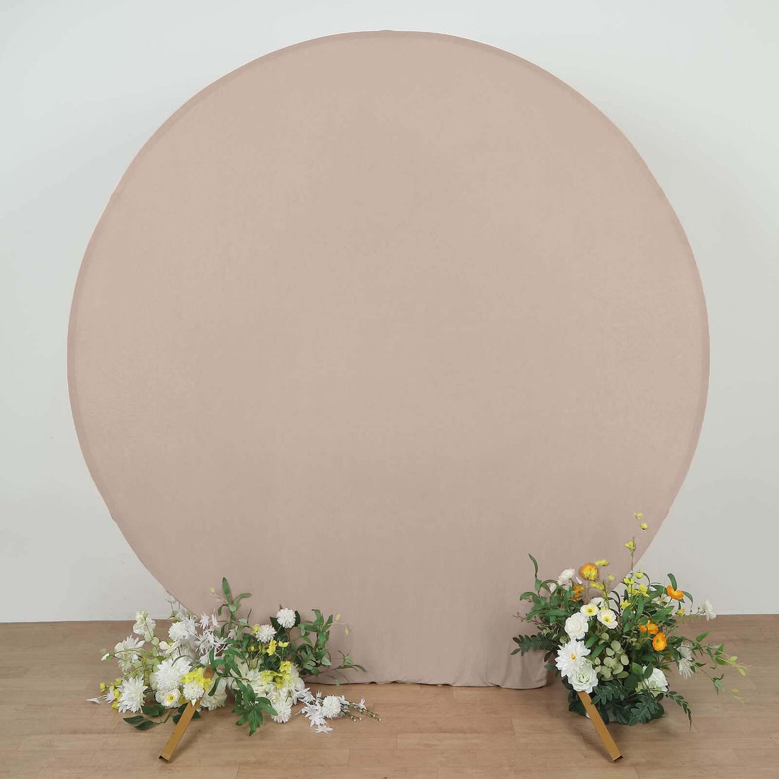 Neutral round backdrop with floral arrangements on both sides.