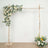 Wooden wedding arch adorned with white and yellow flowers.
