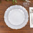 Elegant white plates with scalloped edges and silver rim on wooden table.