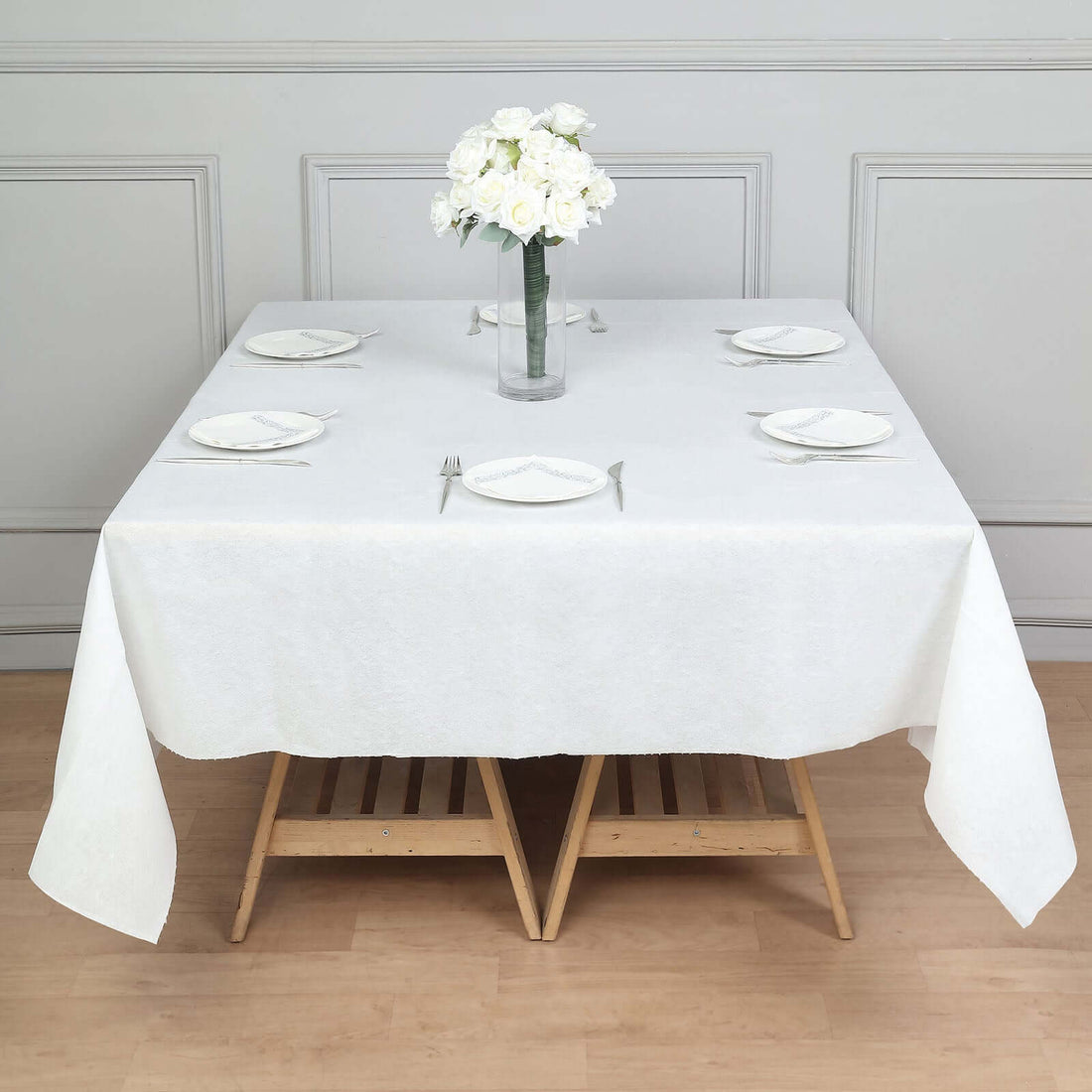 Elegant white table setting with floral centerpiece on a wooden table.