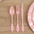 Pink decorative plastic cutlery set on a wooden table.