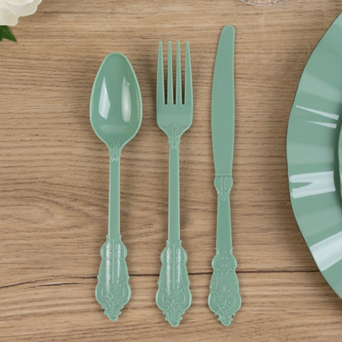 Mint green plastic cutlery set on a wooden table.