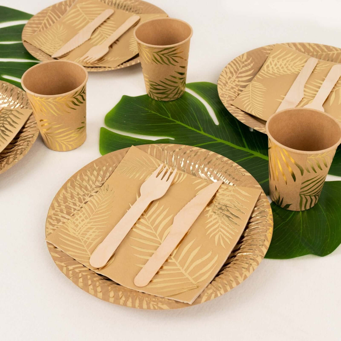 Eco-friendly party tableware with palm leaf design on a tropical setting.