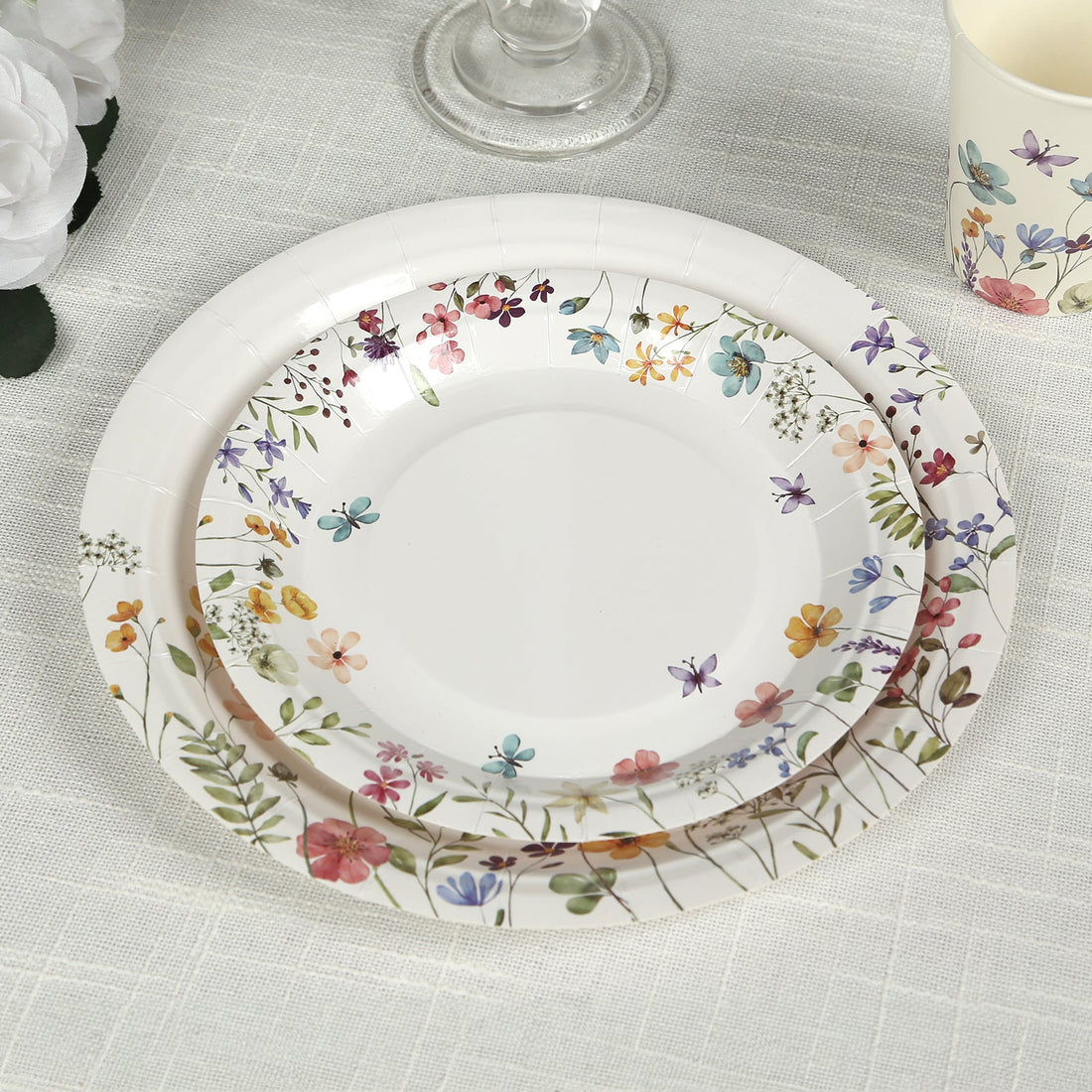 Floral-patterned disposable plates stacked on a light tablecloth.