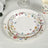 Floral-patterned disposable plates stacked on a light tablecloth.