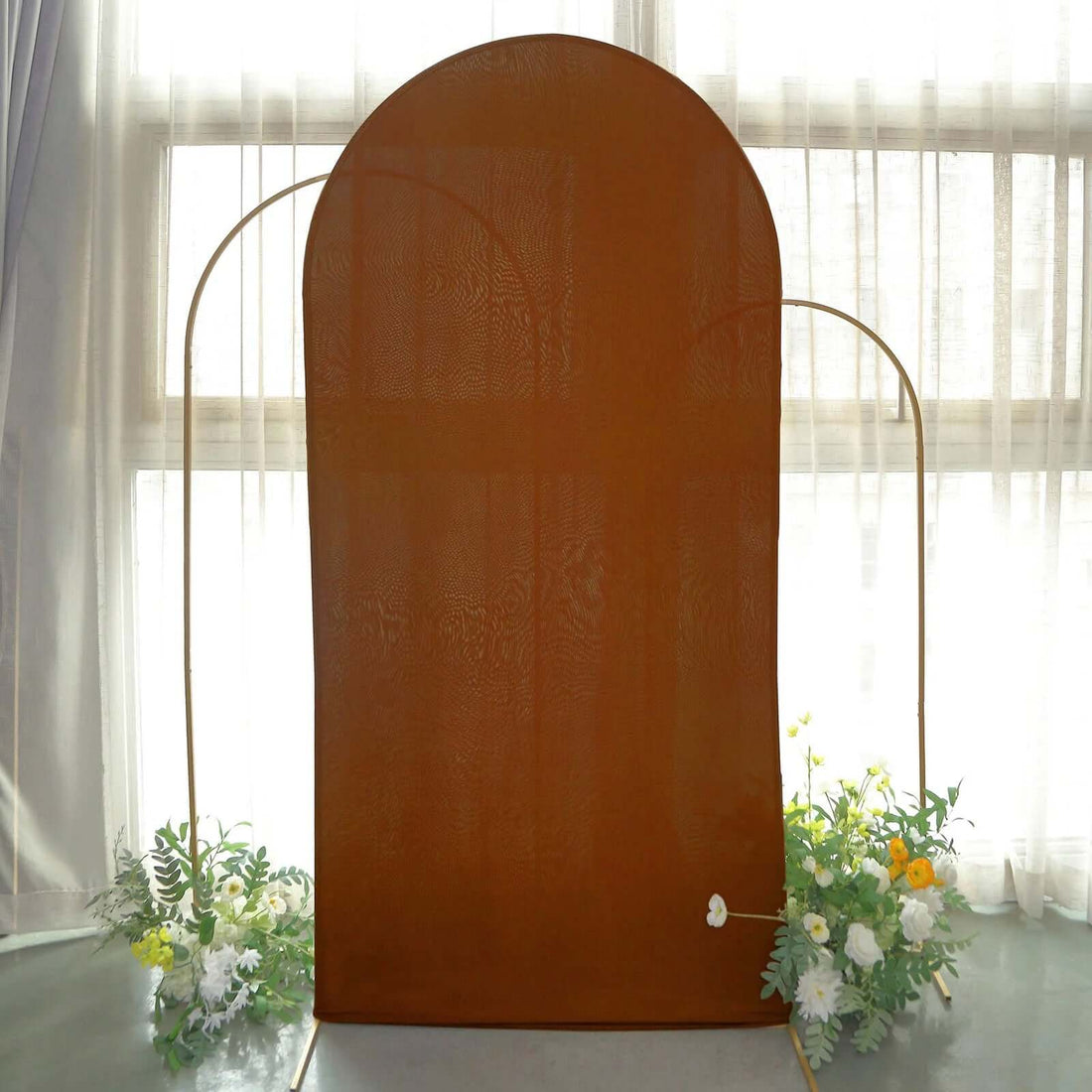 Brown arched backdrop with floral decorations in a studio setting