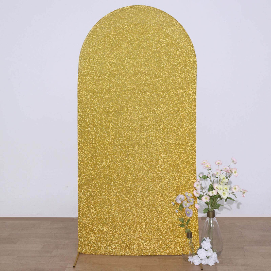 Gold glitter backdrop for photo shoots with decorative flowers.