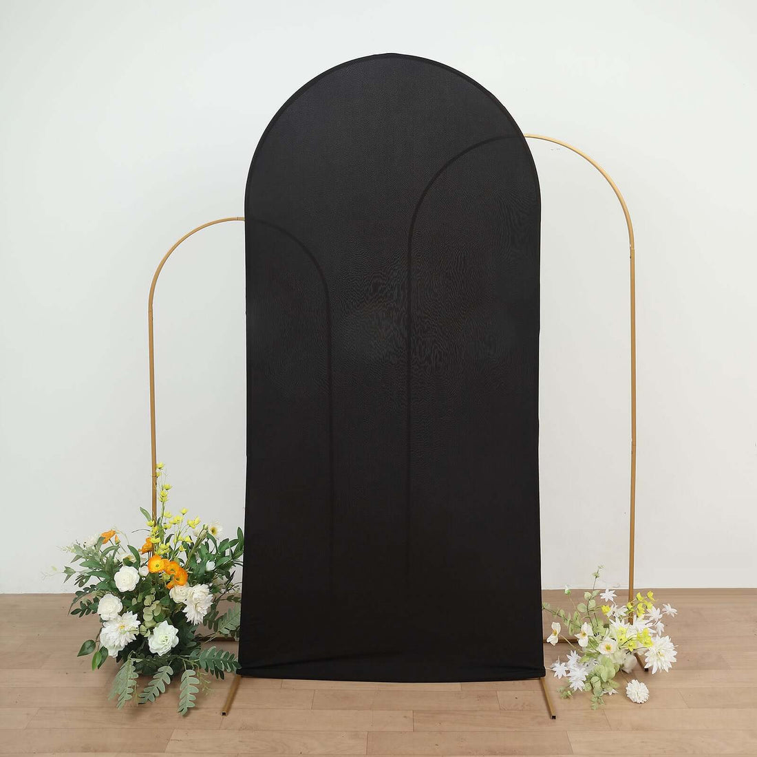 Black fabric backdrop with gold stand and floral arrangements at the base.