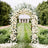 Floral wedding arch adorned with white flowers in a lush garden setting.