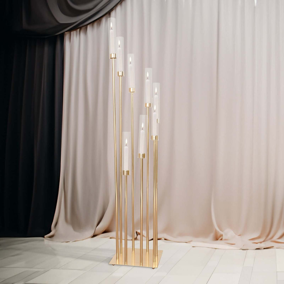 Elegant gold floor lamp with multiple glass shades against draped fabric backdrop.