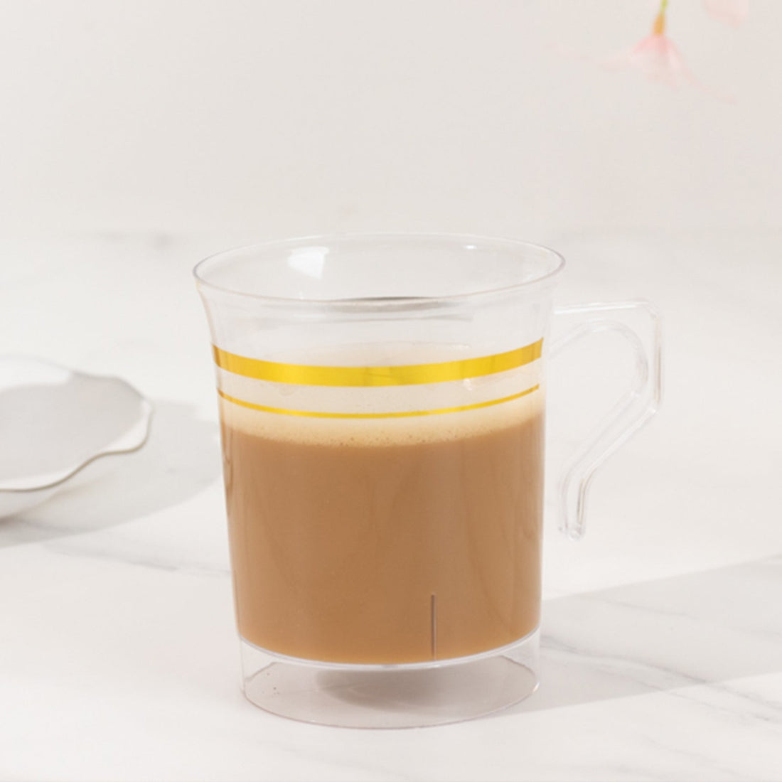 Clear coffee mug with yellow stripes filled with coffee.