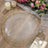 Elegant clear glass charger plate with gold rim on a rustic wooden table.
