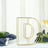 Gold wire letter "D" decorative piece on a dining table.