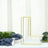 Gold geometric letter "L" decor on a table with greenery and fabric accents.