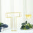 Gold letter "T" table decor with a wine glass and greenery in the background.