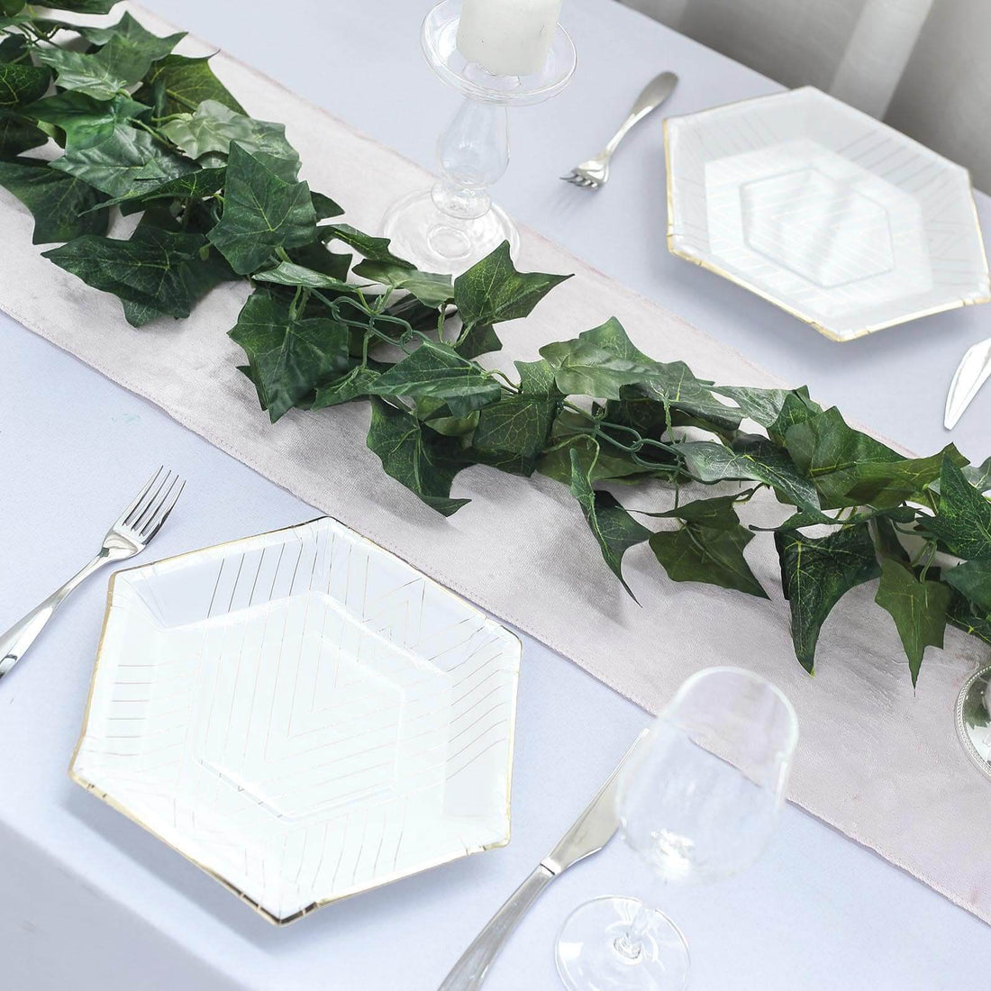 Elegant hexagonal plates on a table with greenery and candle decor.