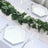 Elegant hexagonal plates on a table with greenery and candle decor.