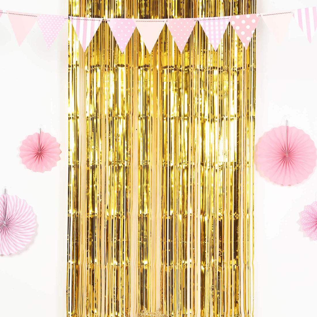 Gold fringe backdrop with pink decorations for parties and events.