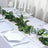 Elegant dining table set with greenery, candles, and fine tableware.