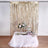 Decorative party table with flowers and treats against a gold fringe backdrop.