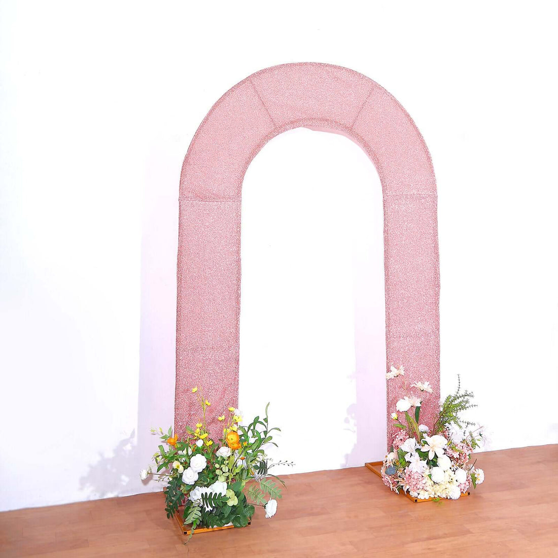 Pink glitter arch with floral arrangements at the base.