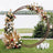Floral wedding arch with roses and pampas grass in a scenic outdoor setting.