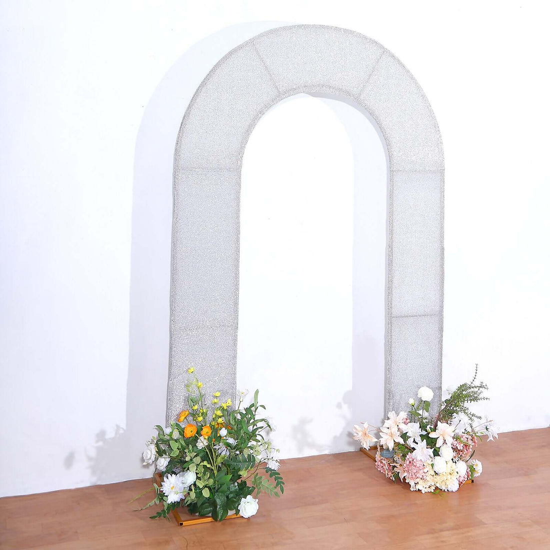 Decorative arch with floral arrangements on the floor.