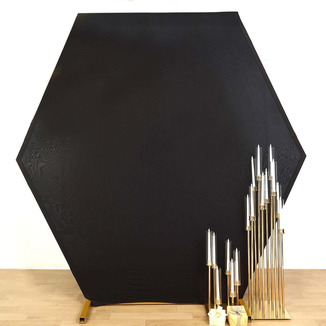 Hexagonal black backdrop with gold support and tall candle holders.