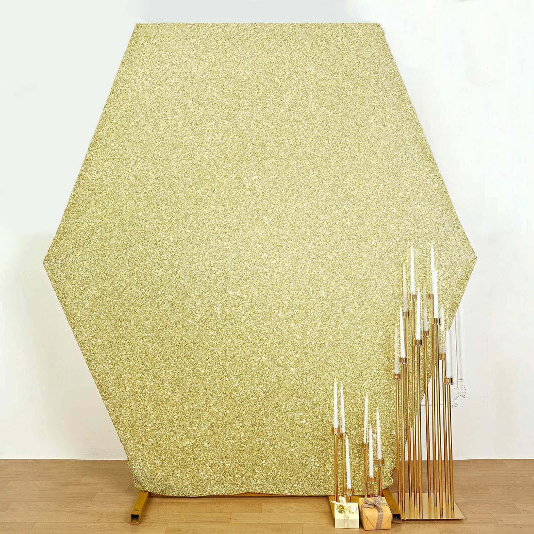 Hexagon-shaped glitter backdrop with gold accents and candle holders.