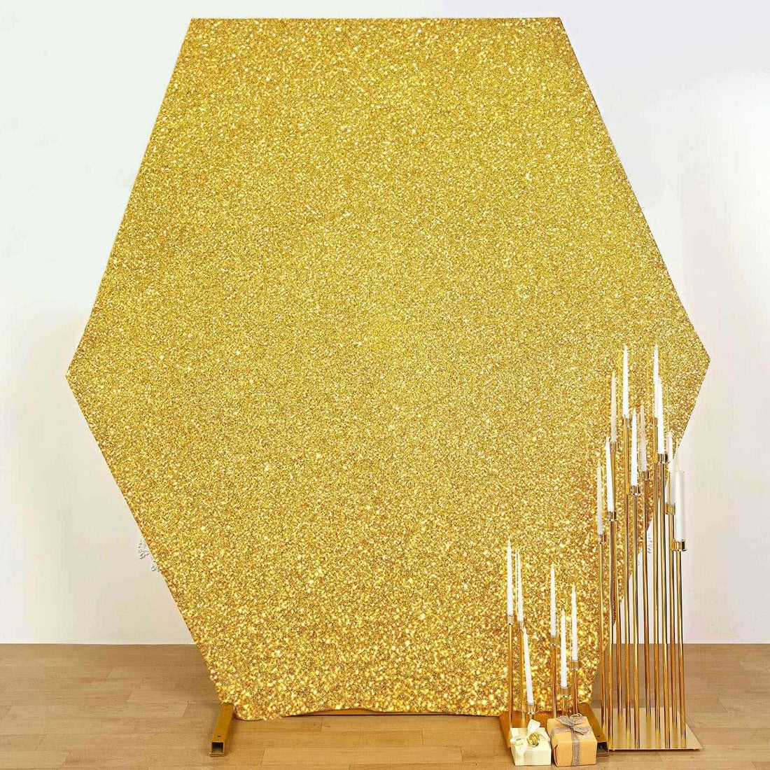 Hexagon-shaped gold glitter backdrop with gold candle holders.