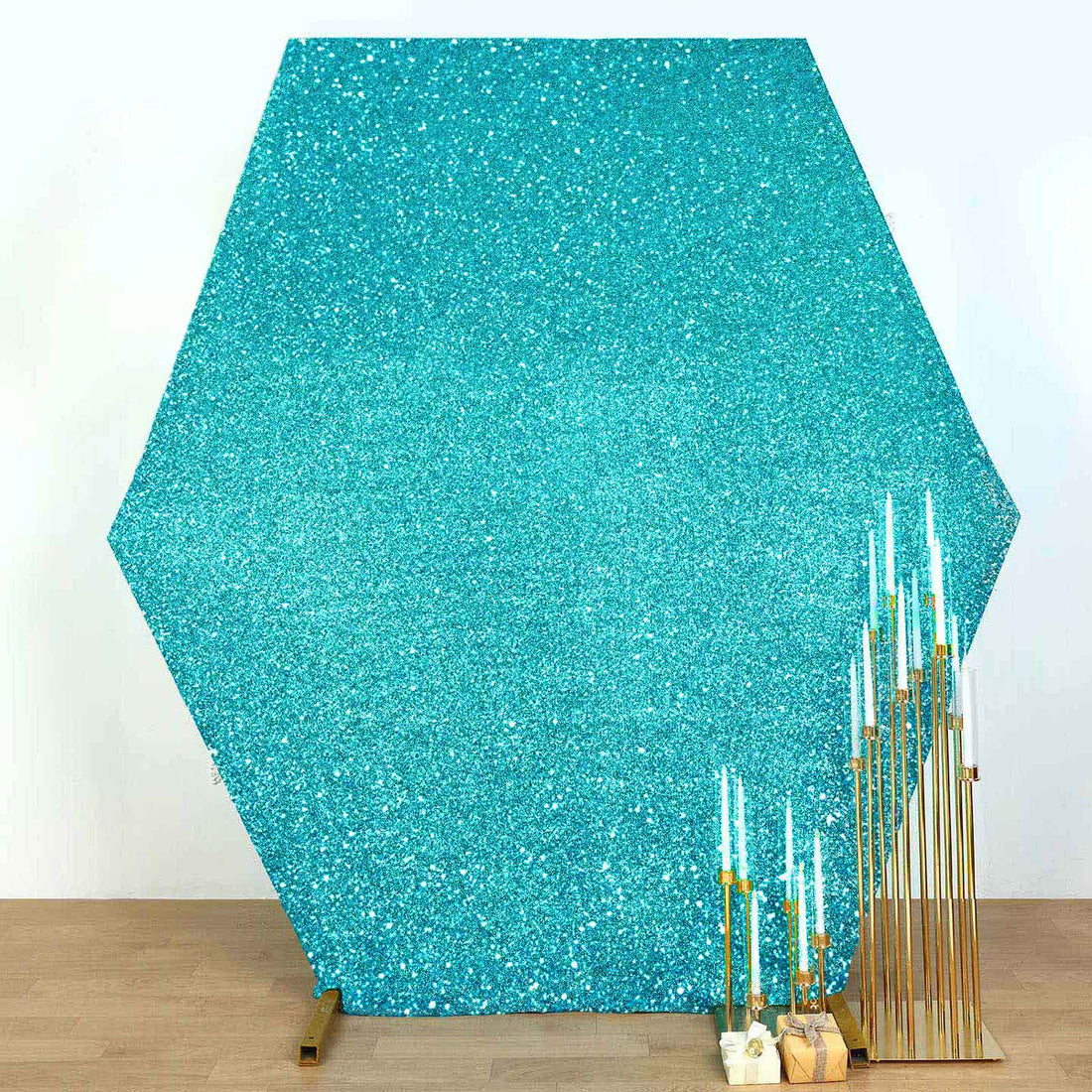 Turquoise glitter hexagon backdrop with gold candle holders and teal candles.