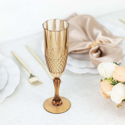 Elegant amber champagne flute on a dining table setting with napkin and flowers.