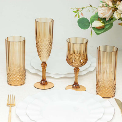 Elegant amber glassware set on a table with white plates and floral decor.