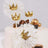 Gold crown cake toppers with tulle accents on a decorated cake.