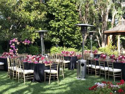 Elegant outdoor event setup with tables, chairs, and floral decorations.