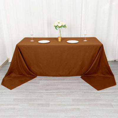 Brown tablecloth draped over a table set with plates and glasses.