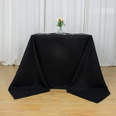 Black tablecloth draped elegantly over a table with floral arrangement and glasses.