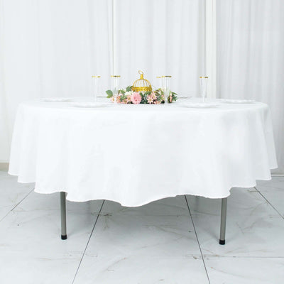 Elegant round table set with a white tablecloth and floral centerpiece.