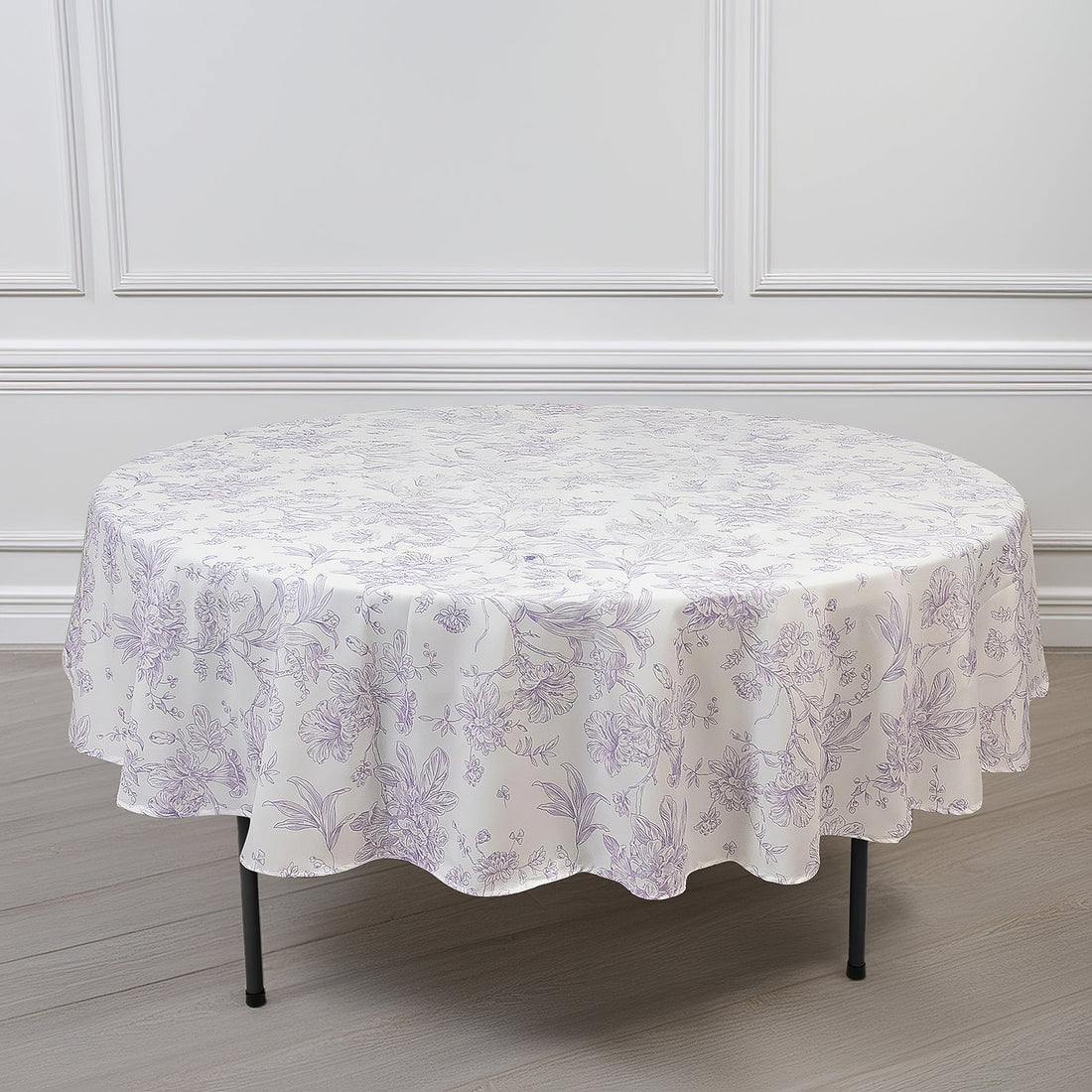 Round floral tablecloth in lavender on a plain backdrop.